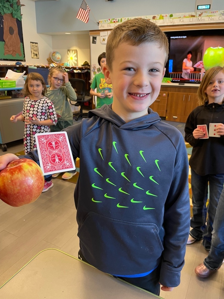 Student holding an apple with a card stuck in it.