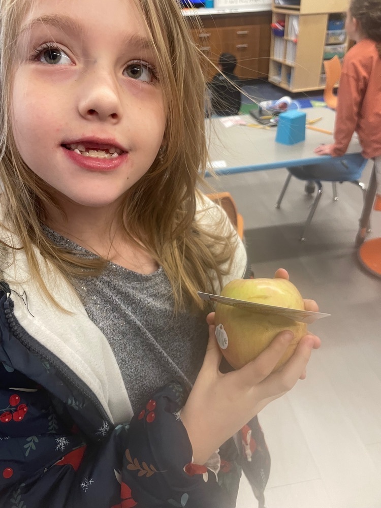 Student holding an apple with a card stuck in it.