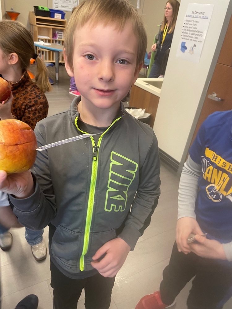 Student holding an apple with a card stuck in it.